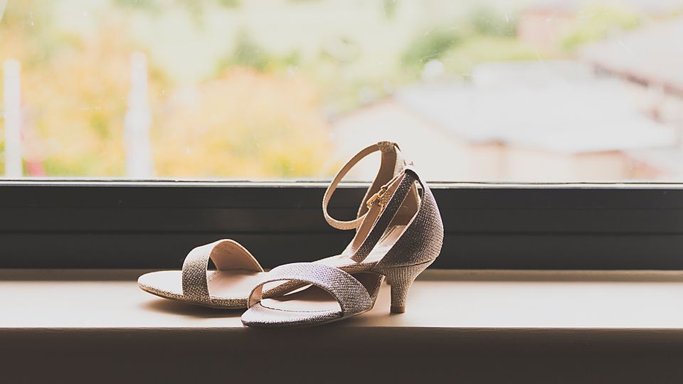 A series of leather sandals and shoes displayed in a row on a windowsill with natural lighting.