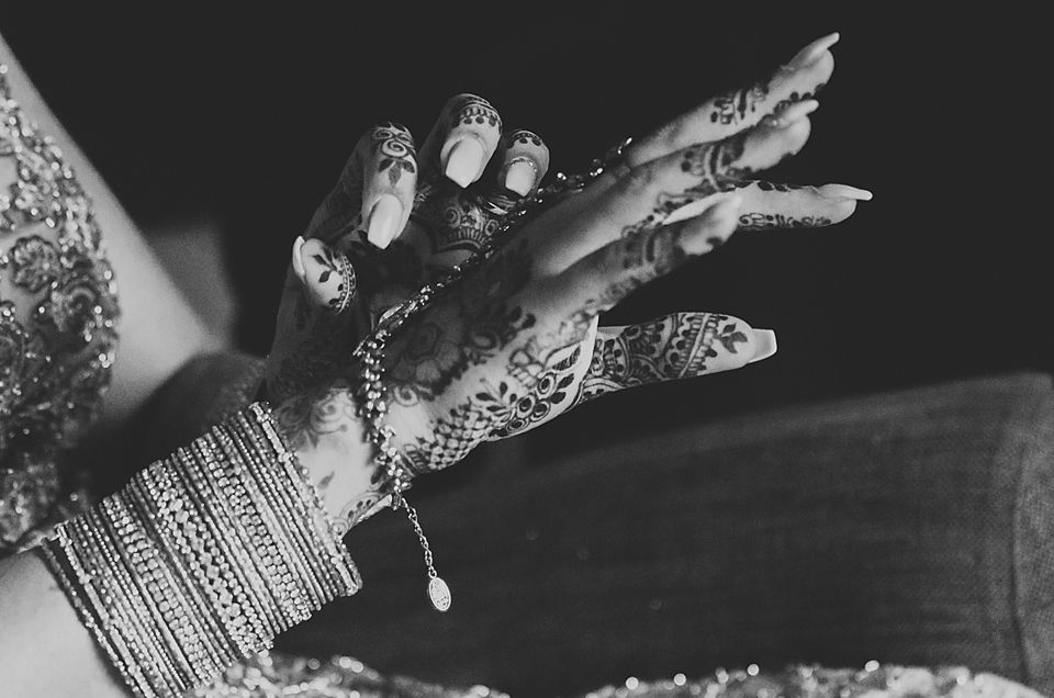 A series of black and white photos showing hands adorned with intricate henna designs and jewelry.