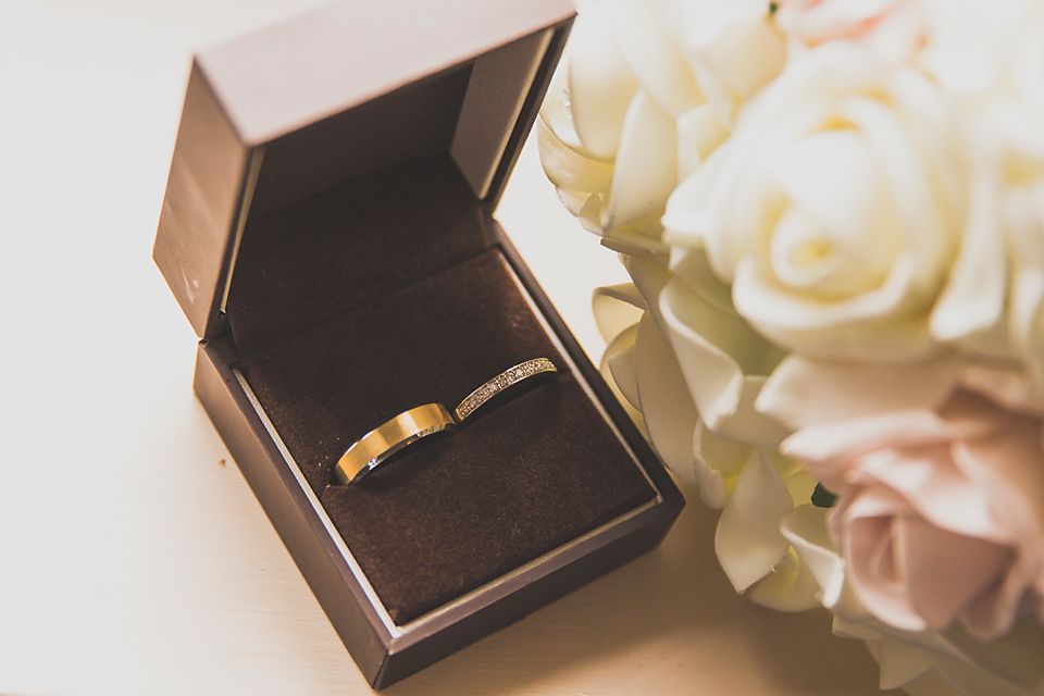 Gold wedding rings nestled in elegant brown jewelry boxes with floral decorations.