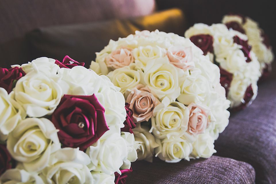 Wedding bouquet with white and burgundy roses arranged in a romantic floral display on dark fabric.