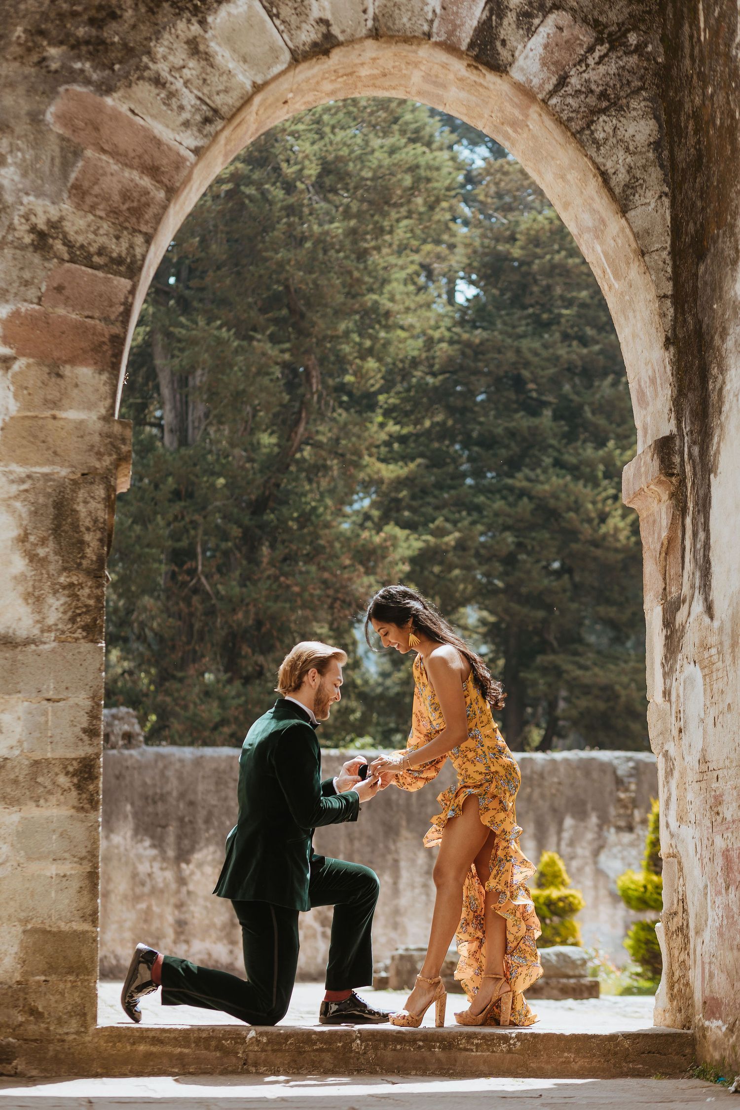 Stone archway corridor in historic venue creates romantic proposal setting.
