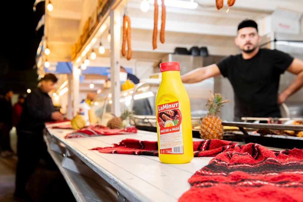 Fresh raw meat is being prepared on a wooden cutting board next to condiments and seasonings in a kitchen setting.