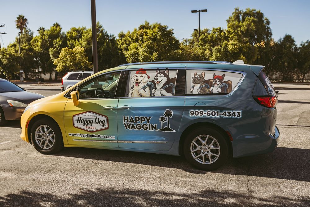 A light blue convertible car decorated with Happy Dog promotional branding and logos parked in a lot.