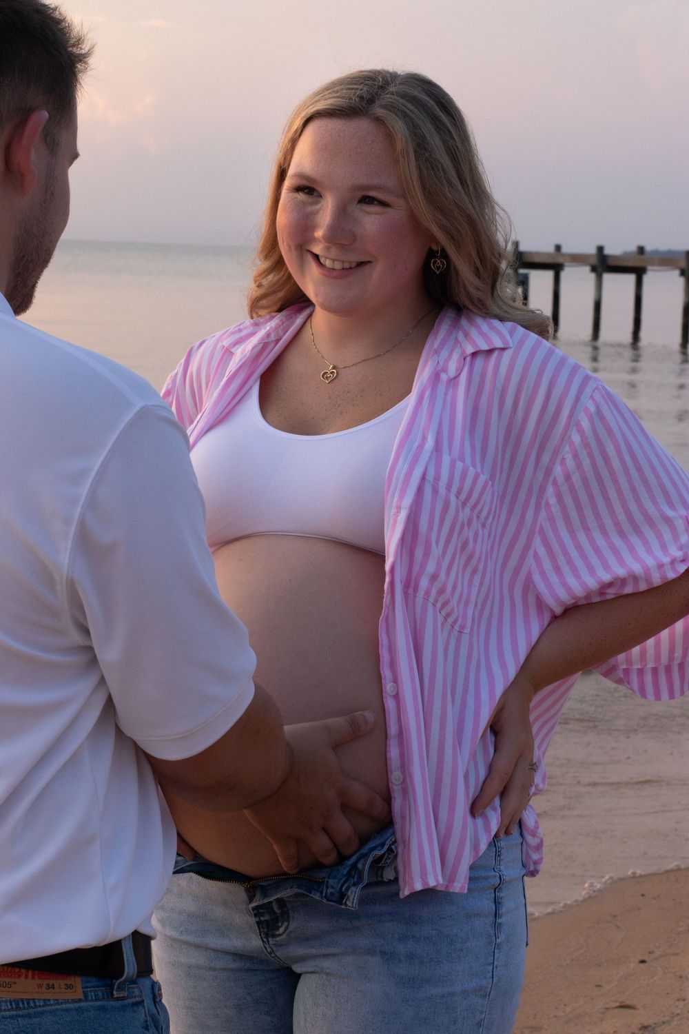 Photo of an expecting mother smiling at her husband at the Fairhope Pier in Alabama.