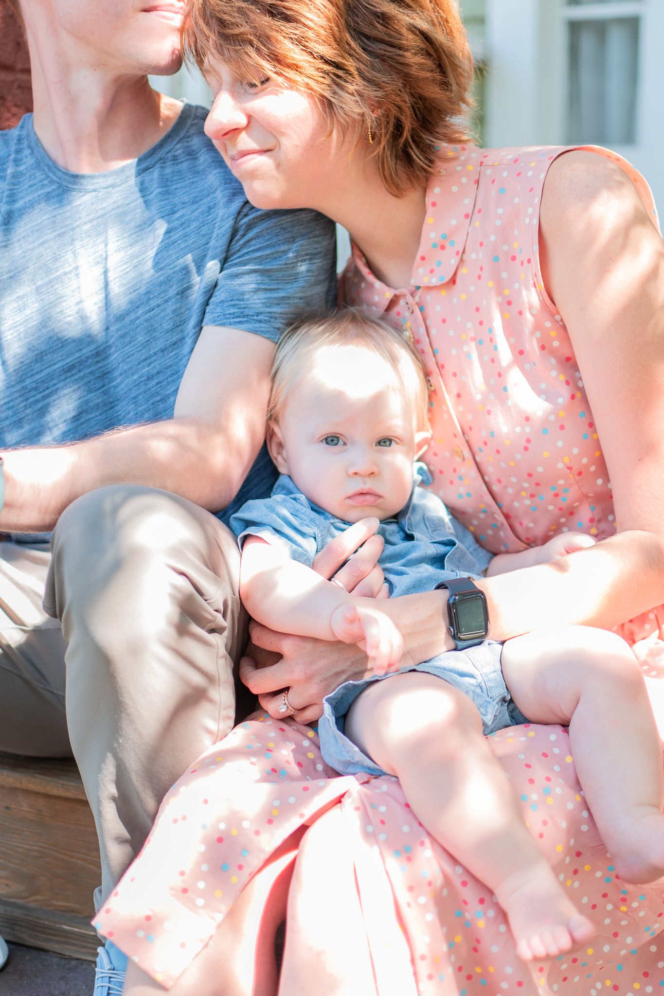 A family sits in the sunlight on their front porch during their at-home family session in Winston-Salem.