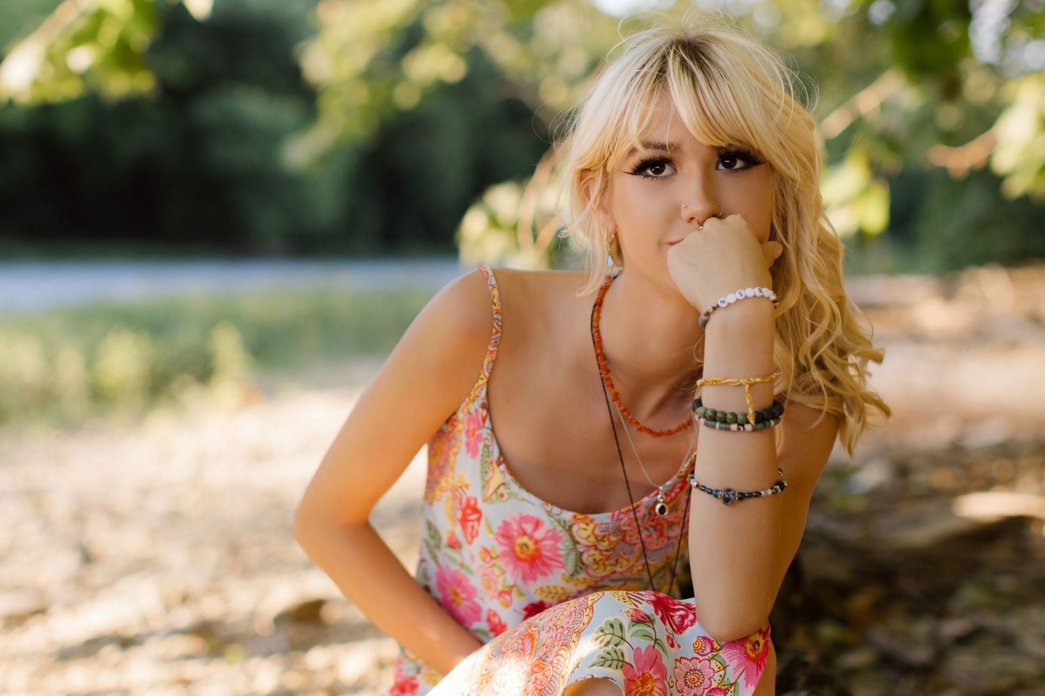 Playful outdoor portrait of someone in a floral sundress making a bubblegum bubble.