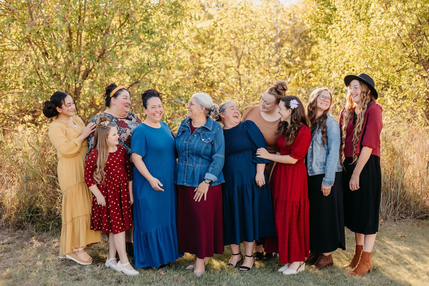 Large group photo of people in coordinated formal attire posed outdoors at sunset.