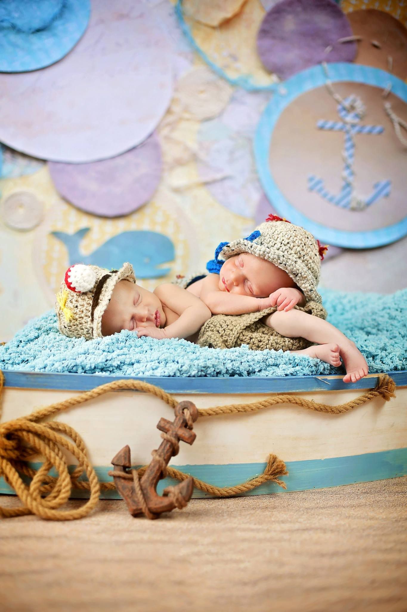 Sleeping twins in sailor hats on blue background with nautical decorations.