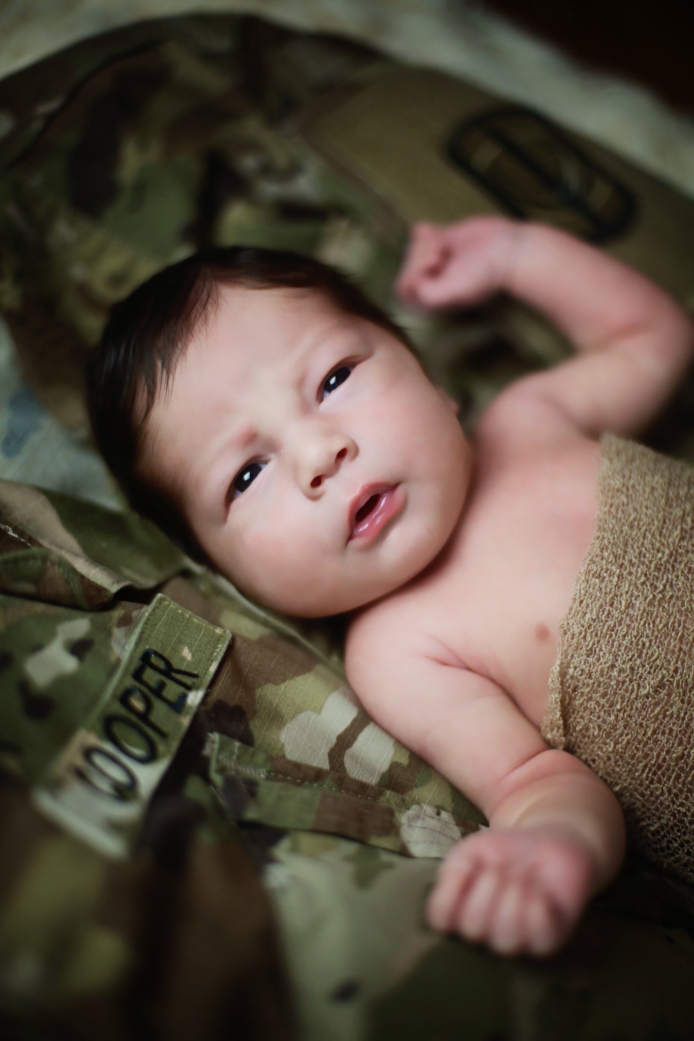 Baby resting on military camouflage uniform fabric.