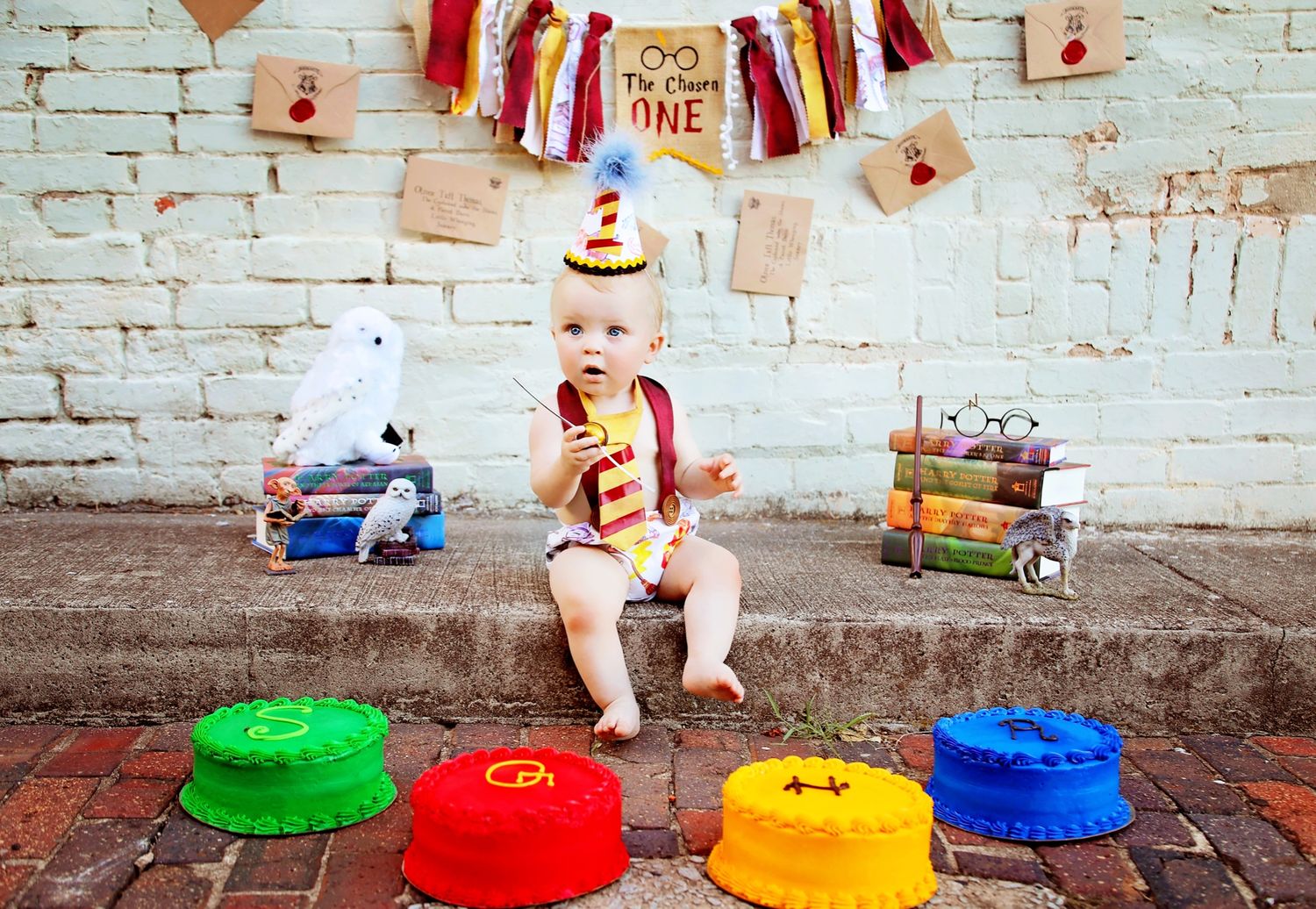 A baby in a vintage-styled first birthday setup with colorful cushions and party decorations.