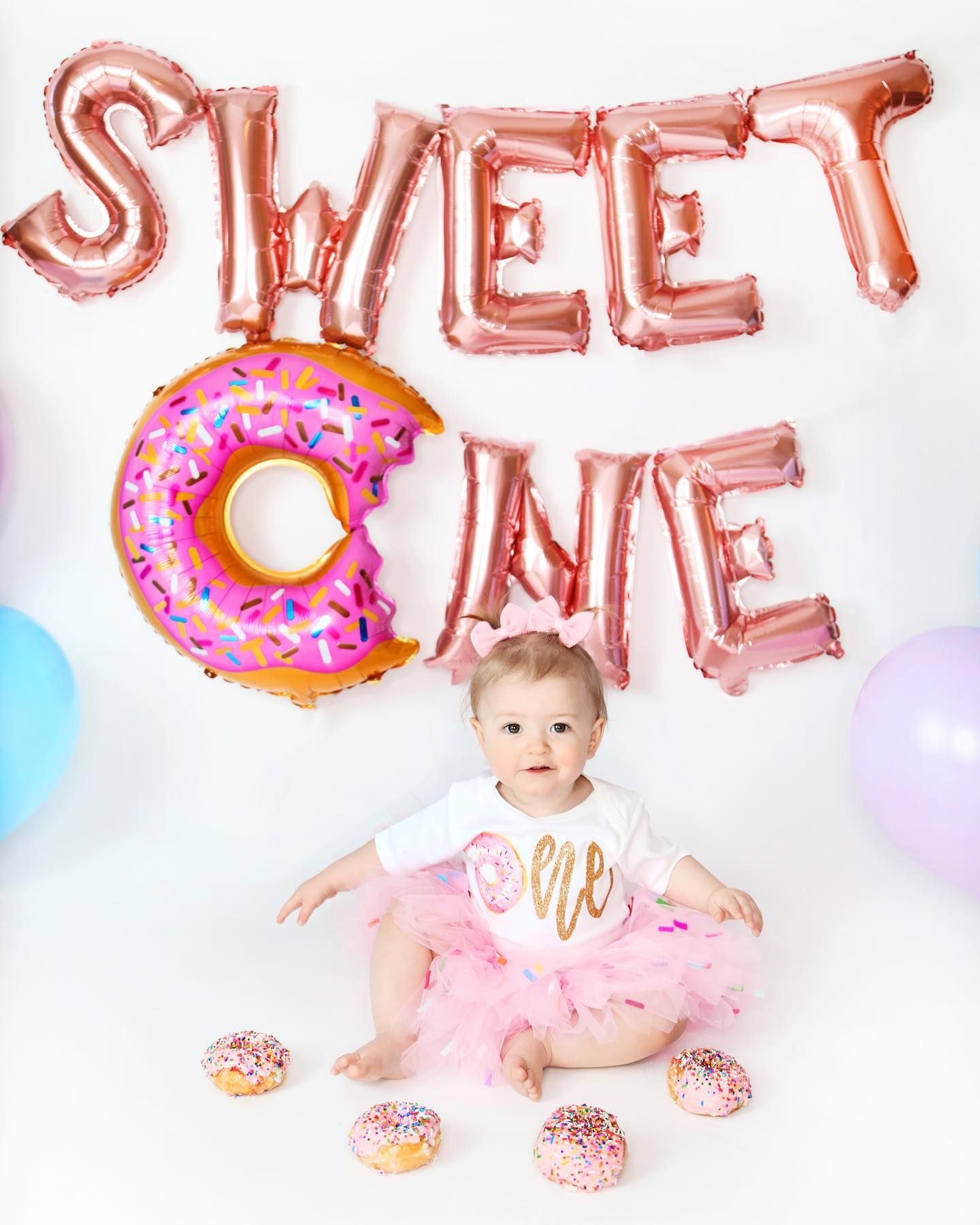 Sweet One birthday setup with pink balloon letters and donut theme decorations.