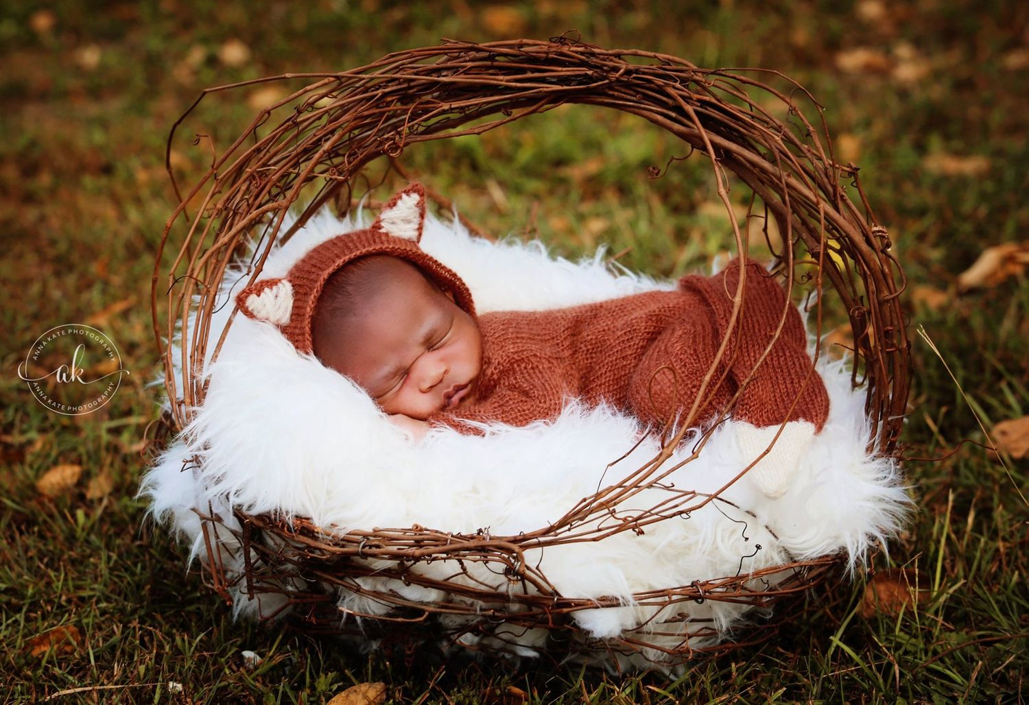 Sleeping newborn nestled in cozy white fur inside rustic twig wreath basket outdoors.