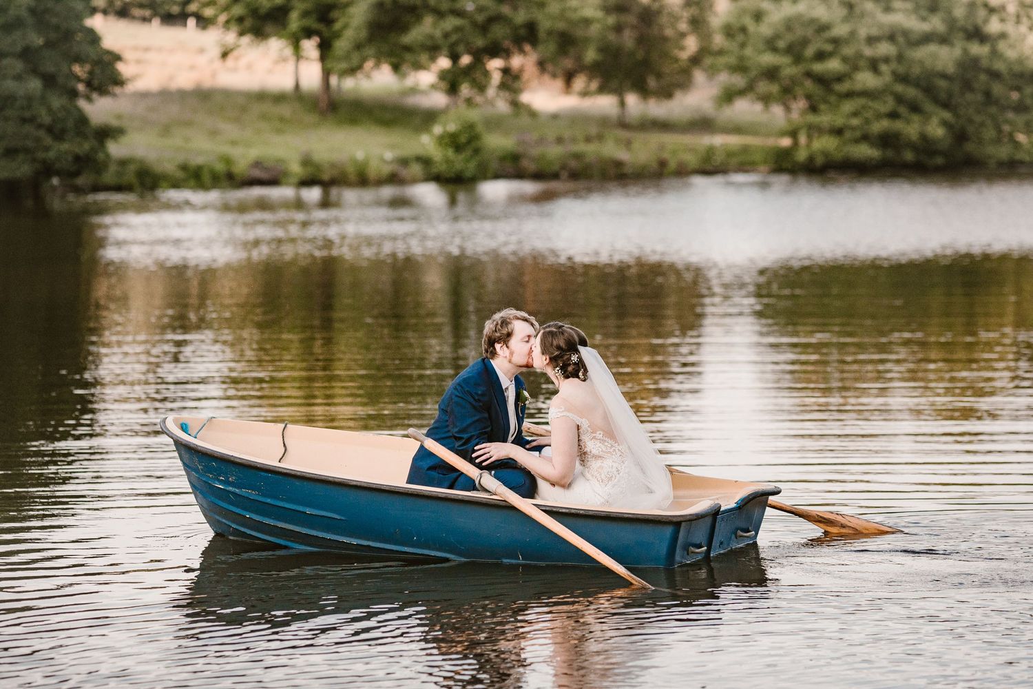 bride and groom kiss in a blue boat on browsholme lake