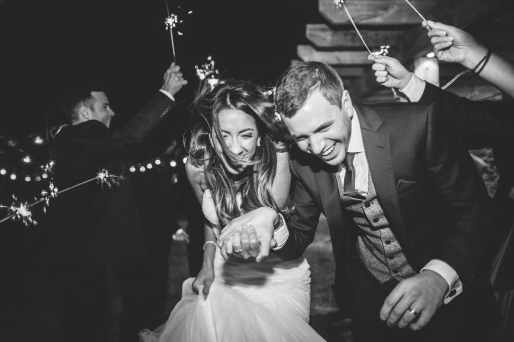 a bride and groom at the shireburn arms run through a sparkler exit with smiles on their faces