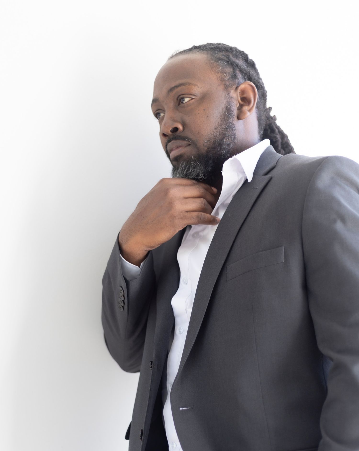 Professional portrait of person in grey suit and white shirt against light background.