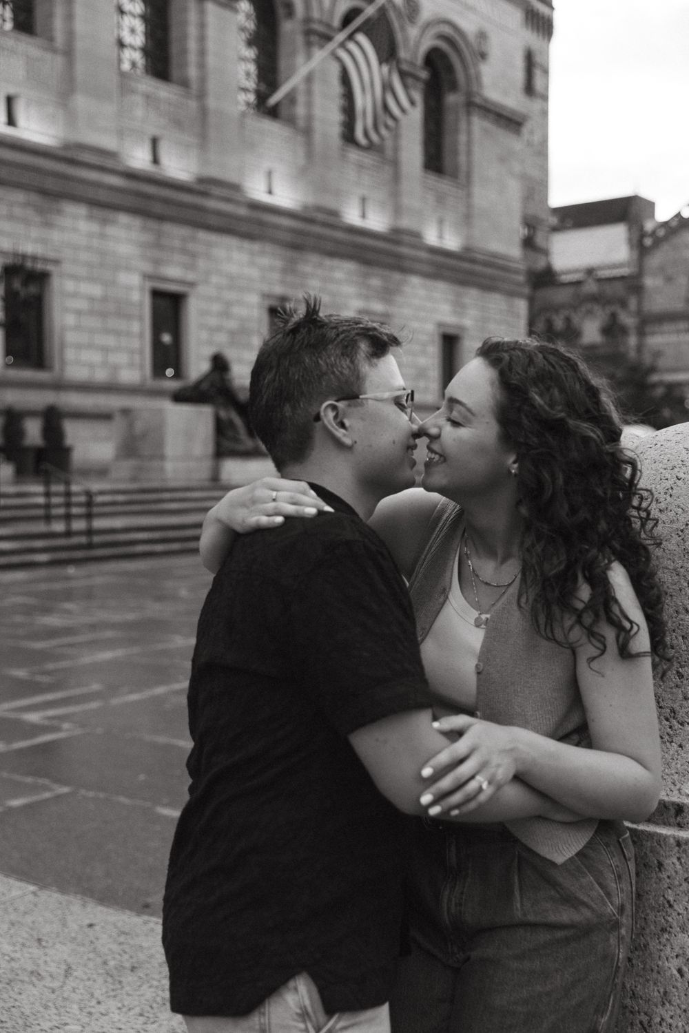 Black and white photos of a couple sharing romantic moments outside a historic building.