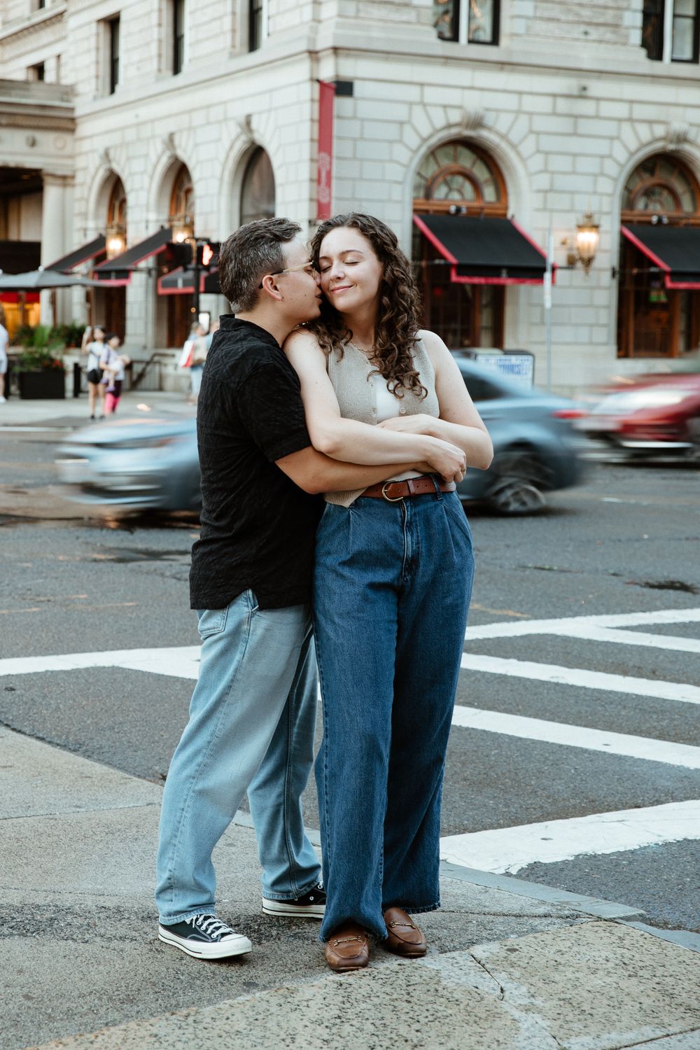 Couple sharing intimate moments on a city street corner with classic architecture.