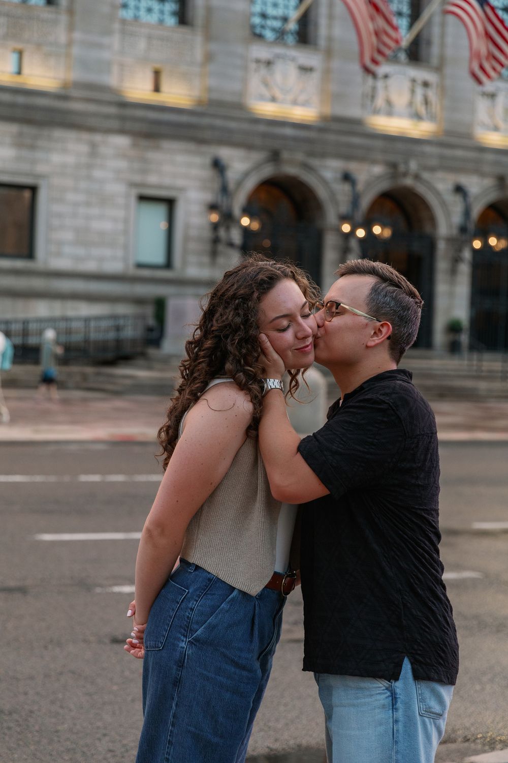 Couple shares affectionate moments outside Boston Public Library.