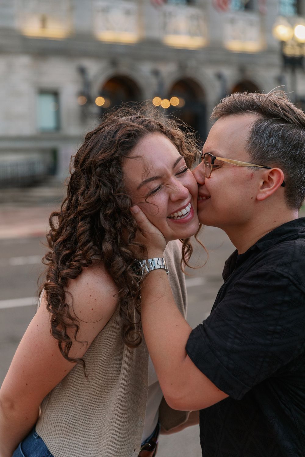 Candid romantic moments captured outside urban building at dusk.