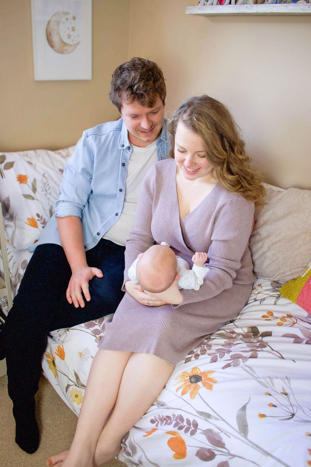 Couple sitting together on floral patterned bedding during maternity photo session.