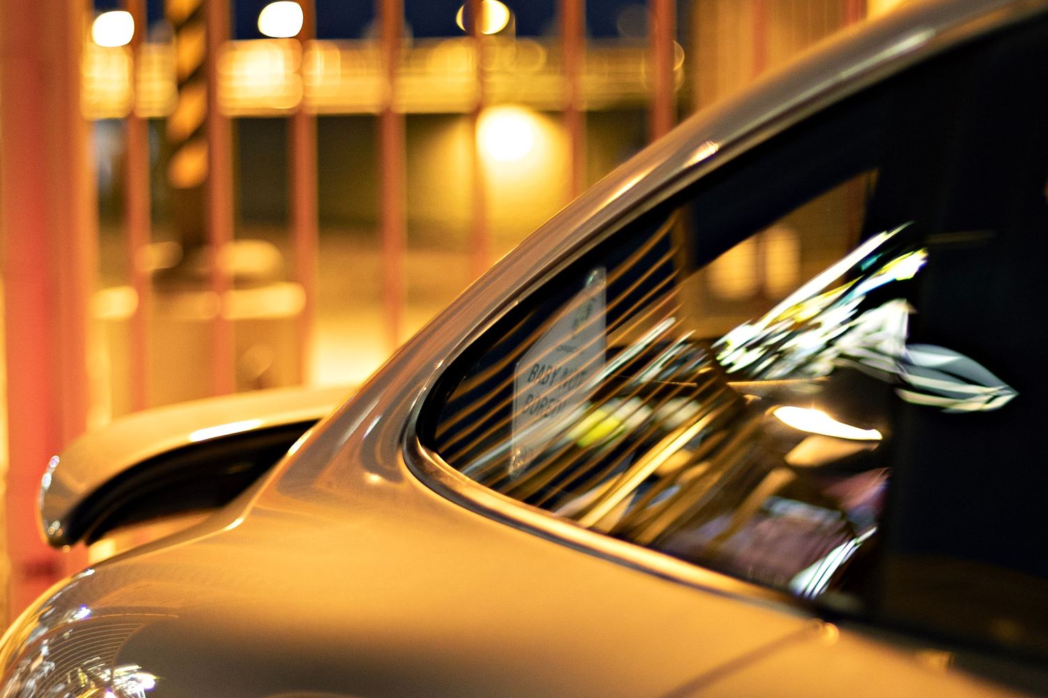 Artistic nighttime shot showing car window reflections with bokeh lights.
