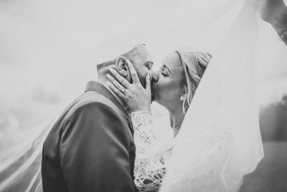 Black and white intimate wedding moment captured through flowing veil.