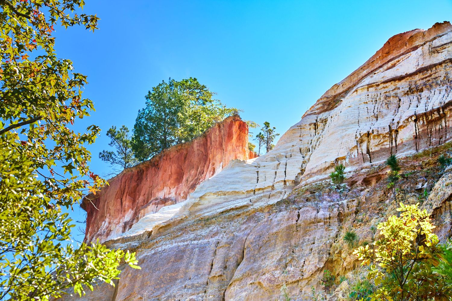 Colorful striped cliff face showing red and white rock layers against vibrant blue sky.