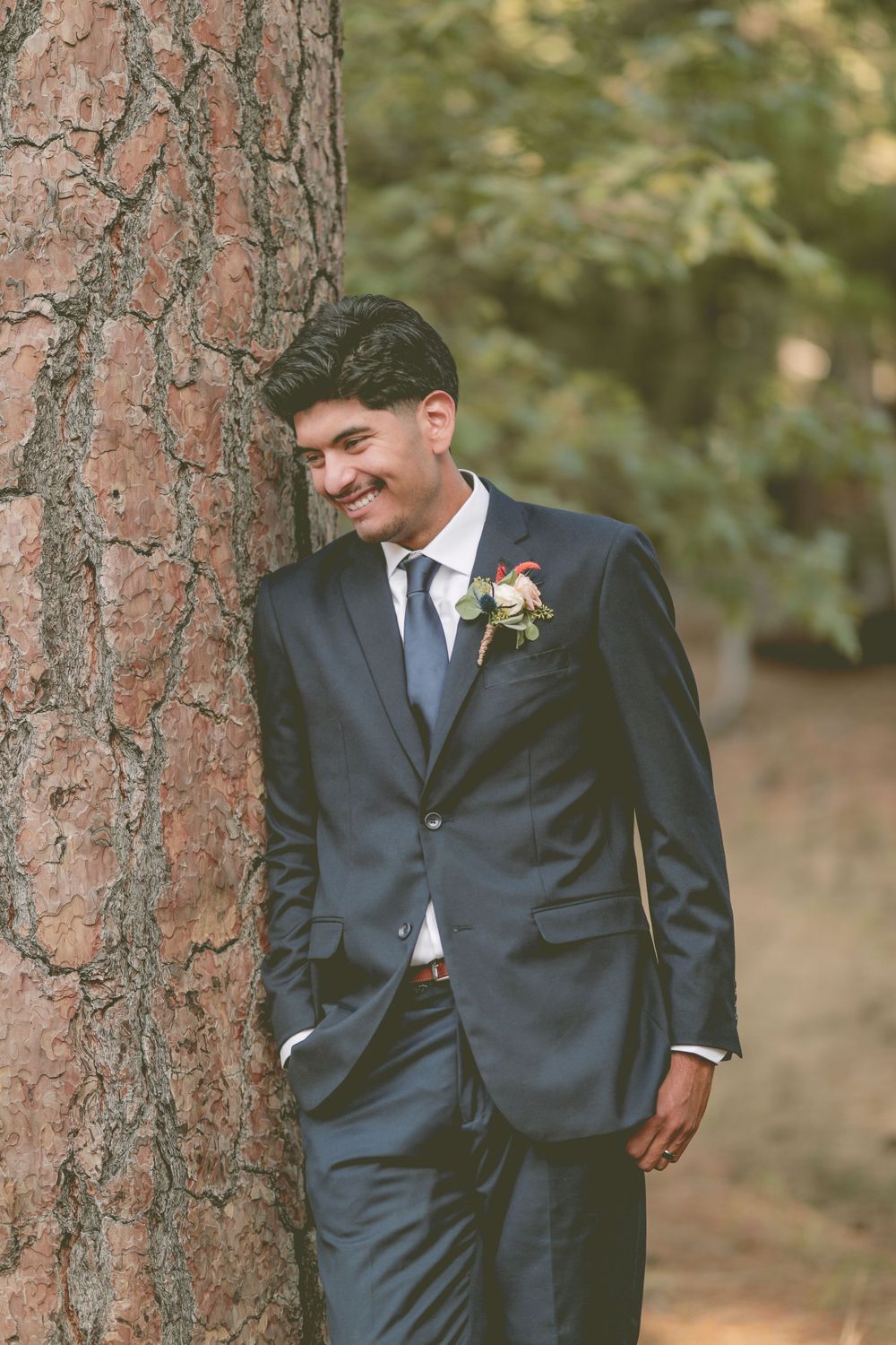 a groom leaning against a tree in big bear california