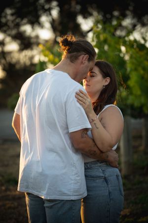 Couple sharing an intimate moment in golden sunset light among garden foliage.