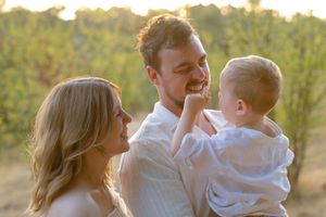 A loving family shares tender moments together outdoors during golden hour sunset.