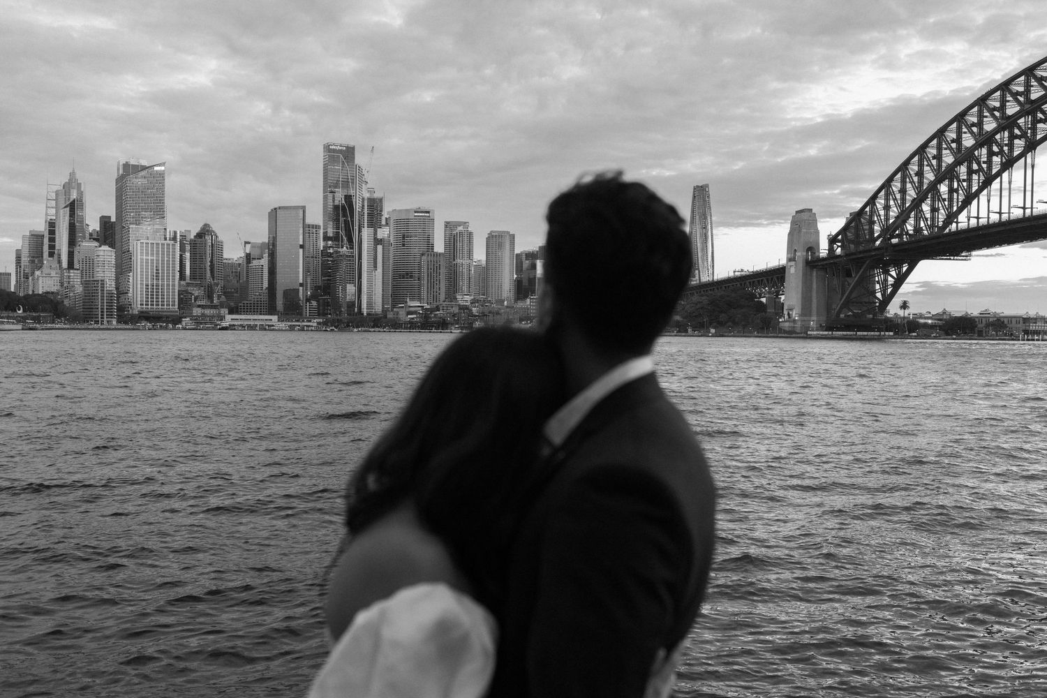 A black and white view of Sydney skyline and Harbour Bridge with a silhouetted figure in the foreground.