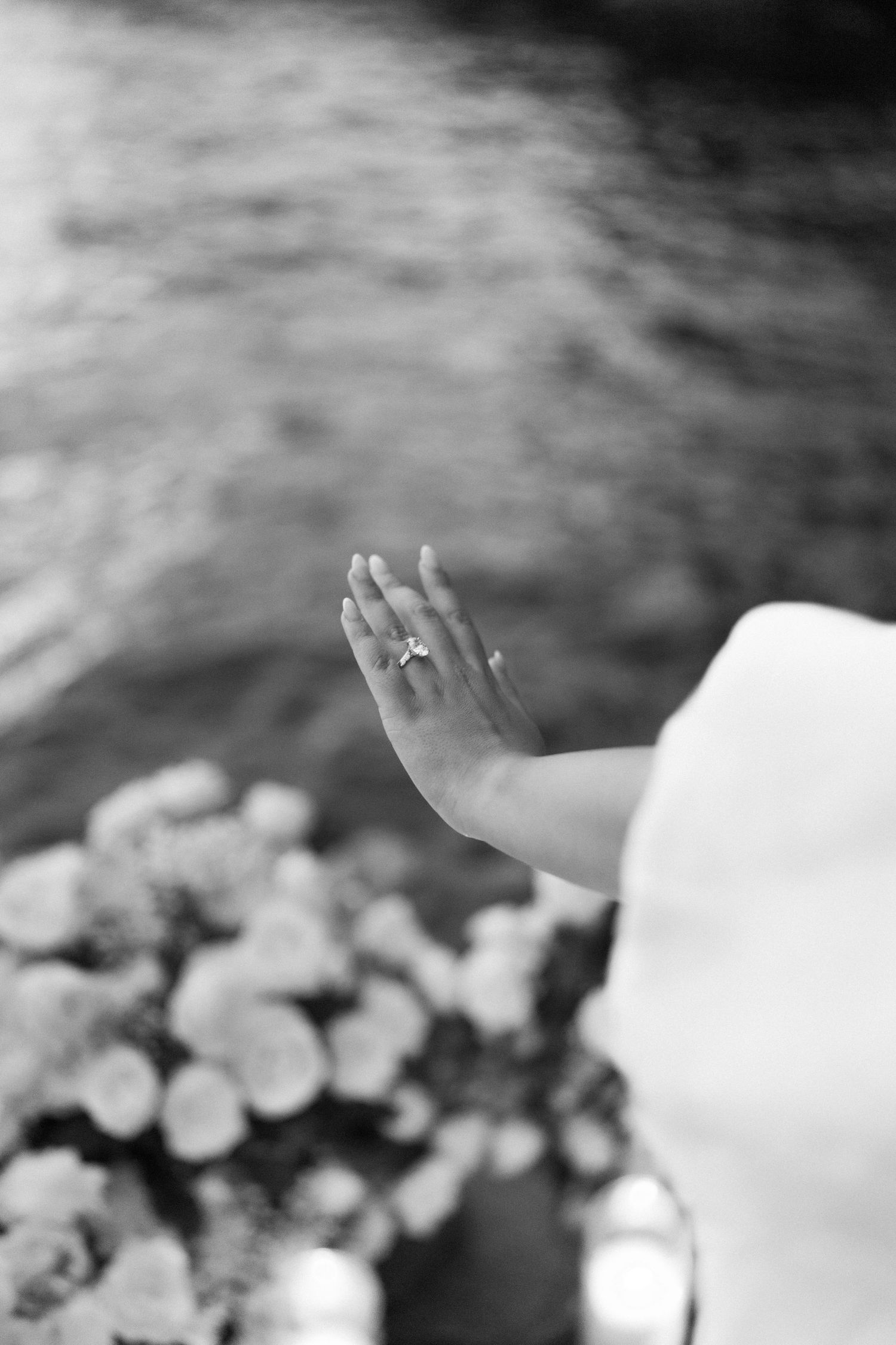 Black and white image shows hands reaching upward against a cloudy sky background.