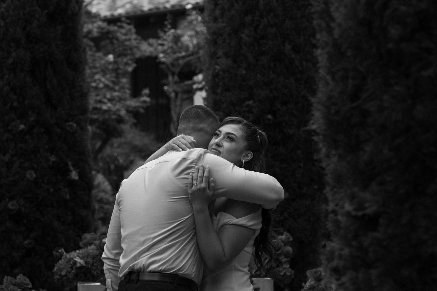 Black and white photo of tender embrace during garden proposal.