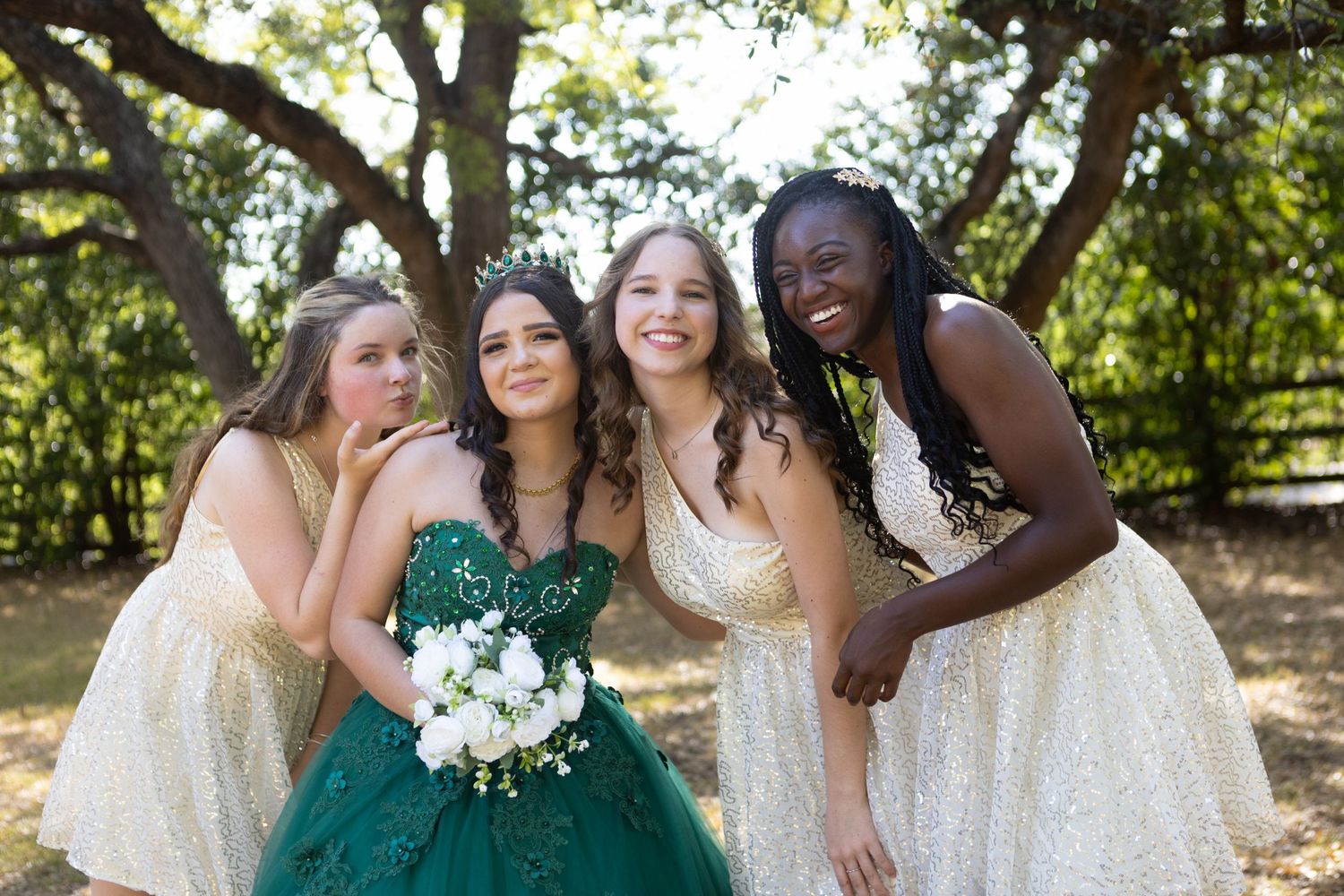 Wedding party members pose together outdoors with bouquet and emerald green dress accents.