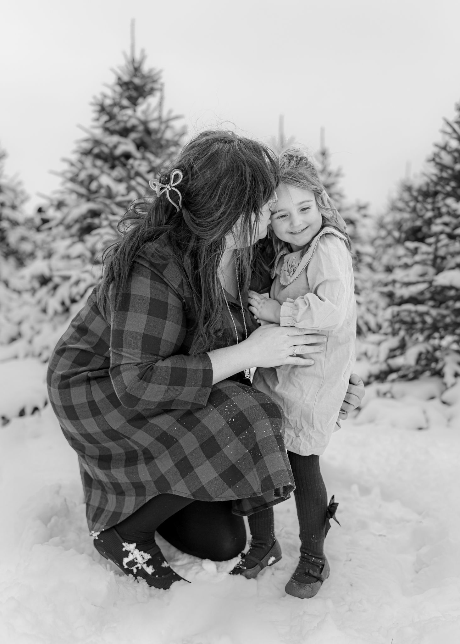 Black and white photo of a winter scene with snow-covered evergreen trees in the background.