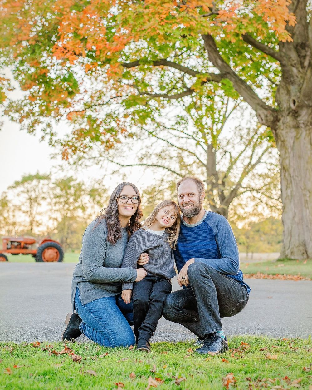 Family enjoying a relaxing autumn day together on grass surrounded by colorful fall foliage in the park.