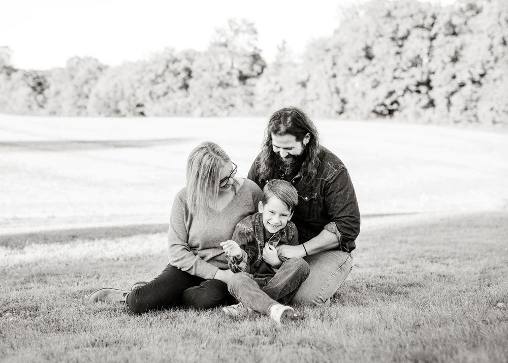 A black and white sequence of photos showing a playful interaction between two people on a grassy hill.