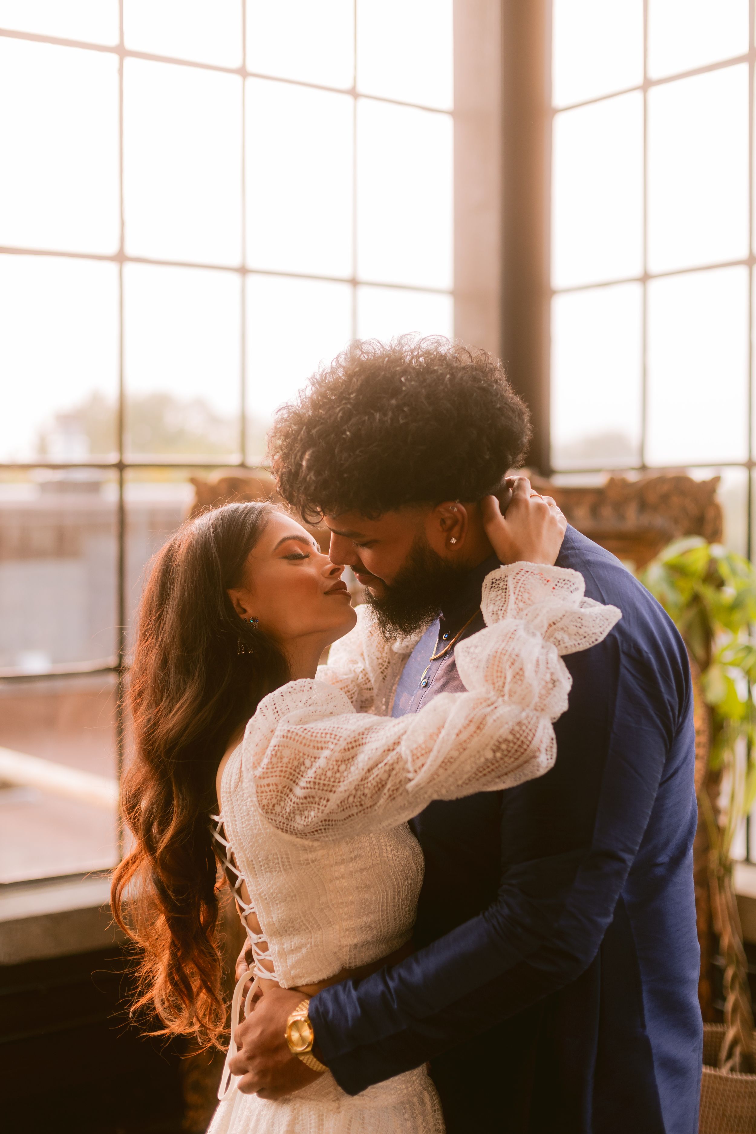 Intimate moment captured in warm sunlight by industrial windows.
