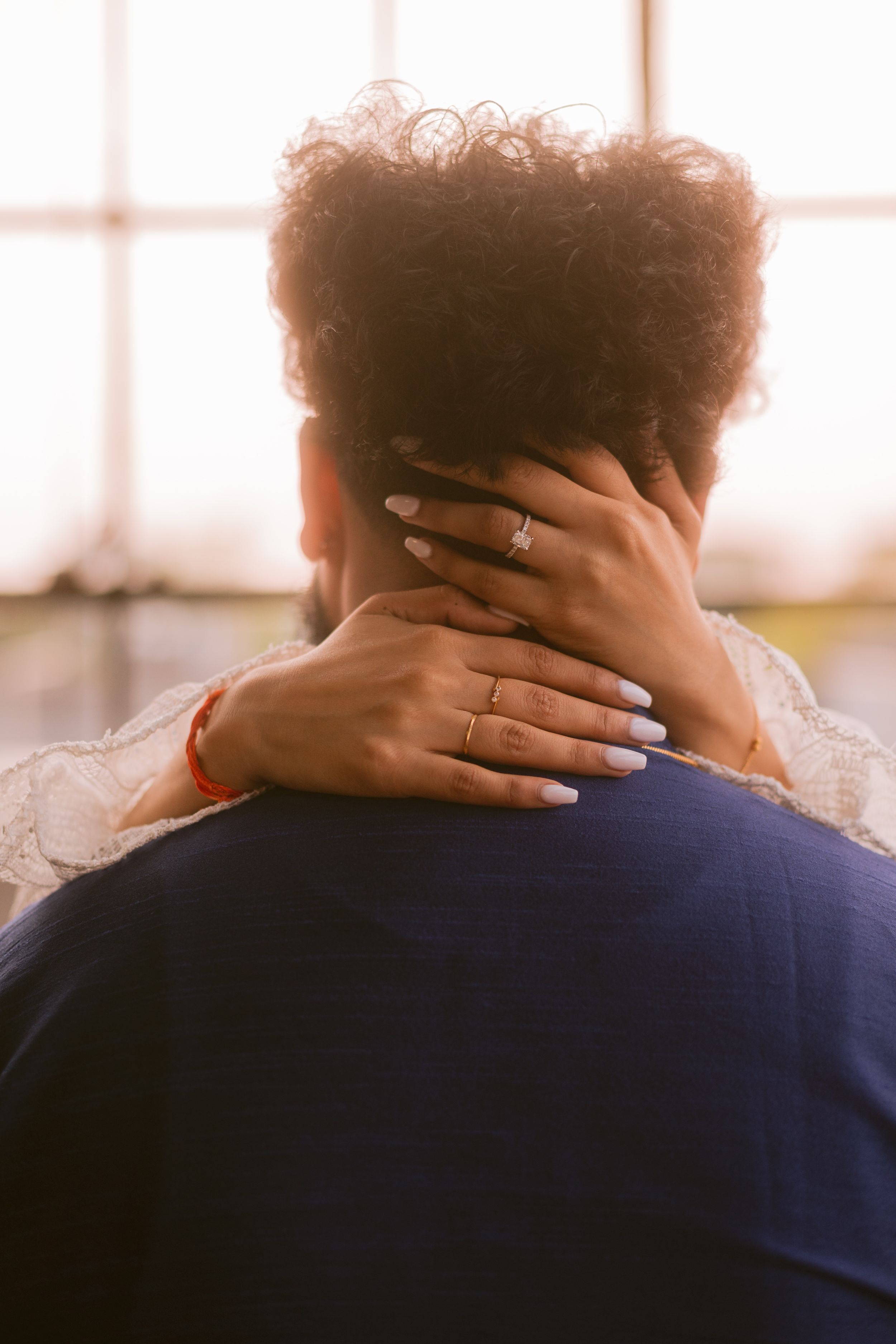 Close-up of embracing couple showing wedding rings and intimate moment.