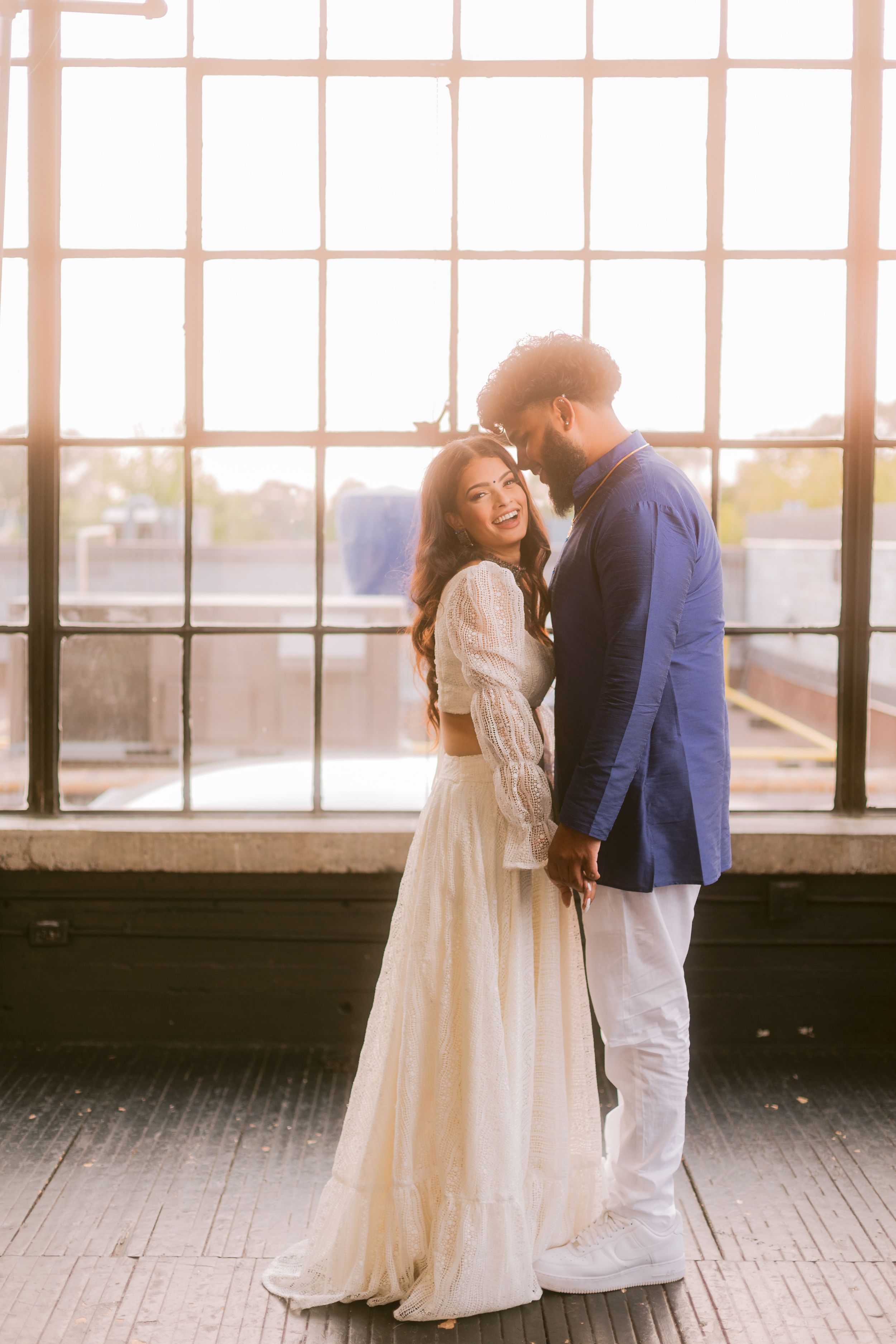 Romantic moment captured by large windows in an industrial style venue.