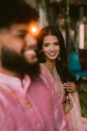 A romantic couple in matching pink outfits share an intimate moment in a dimly lit setting.