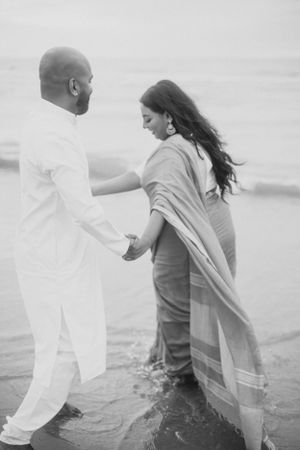 A black and white photo of a couple dancing in the ocean waves.