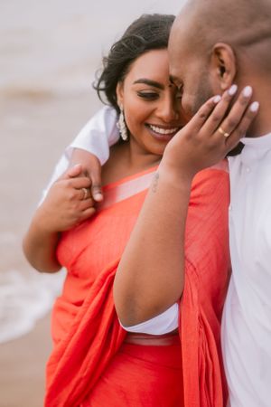 A tender moment between a couple as they embrace, with one wearing a coral-colored sari.
