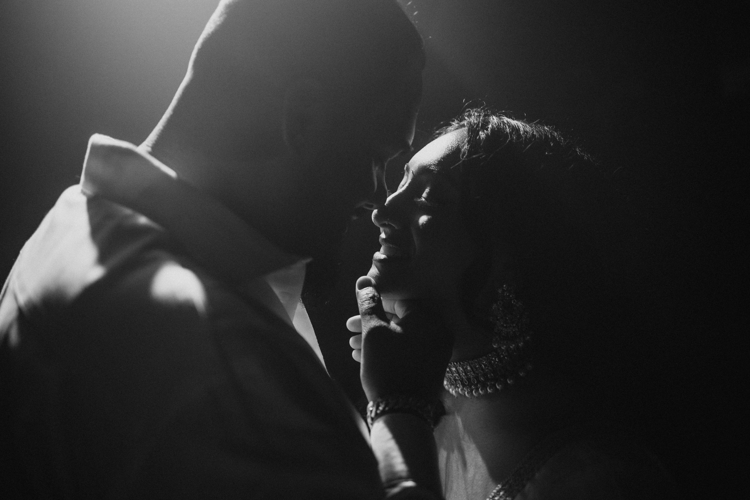 A dramatic black and white portrait of a couple in an intimate moment.