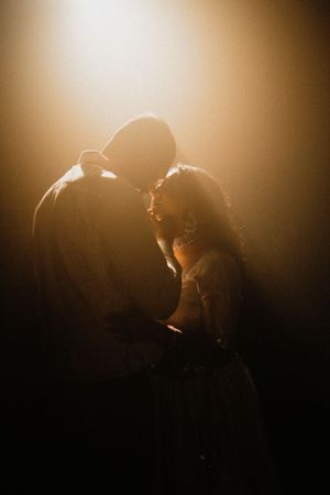 A silhouetted couple shares an intimate moment in warm golden backlighting.