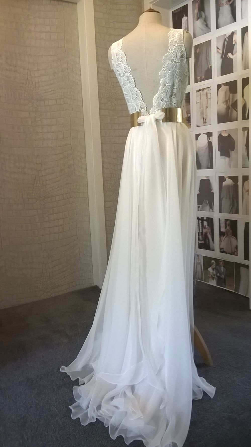 Langes weisses Brautkleid mit goldigem Metallgürtel an einer Schneiderpuppe.