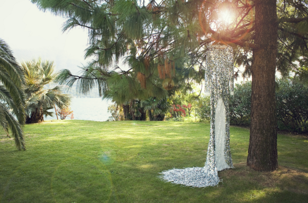 Ein Brautkleid hängt an einem Baum in einem grünen Garten.