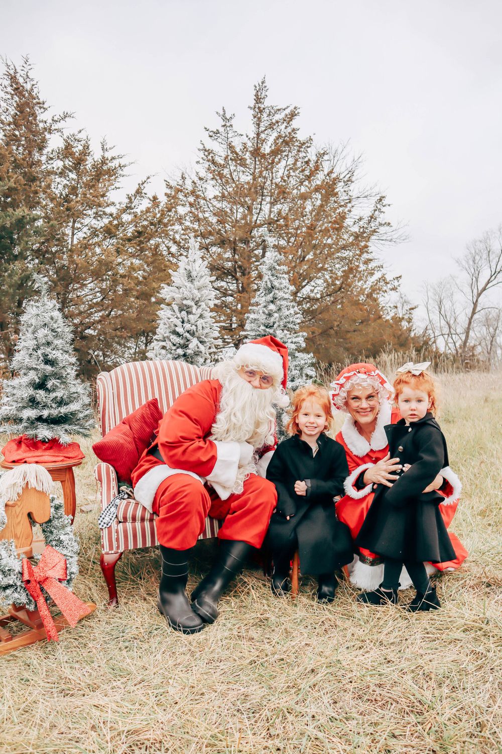 A festive outdoor Christmas scene with decorated trees and a striped armchair.