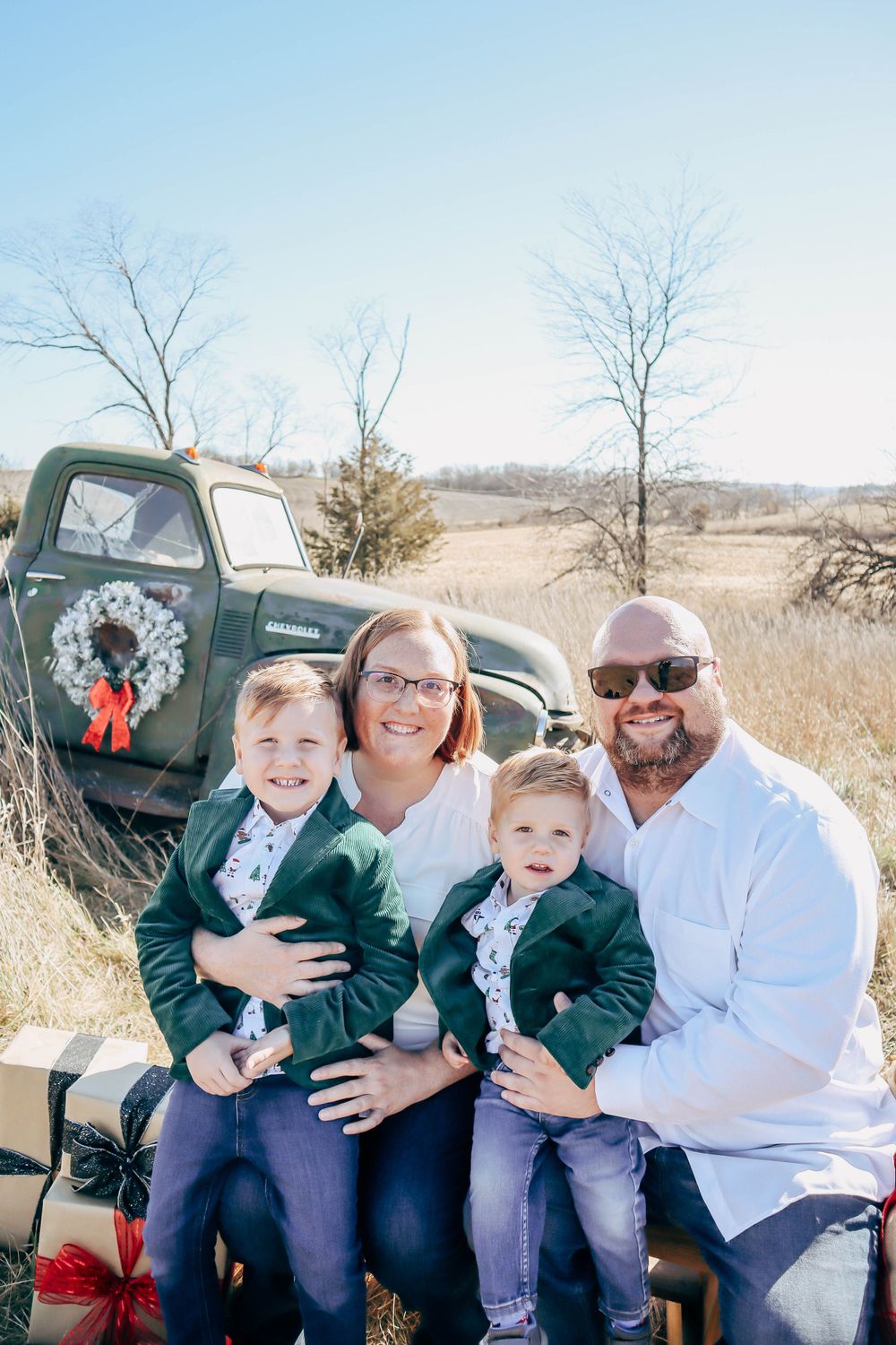 A casual family portrait taken in front of a vintage green truck with a holiday wreath.