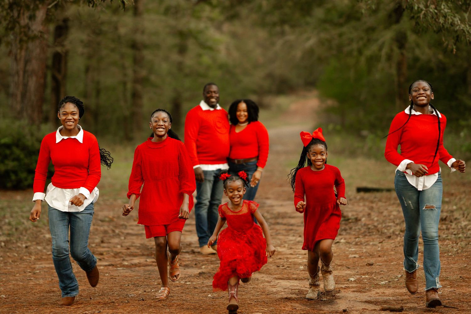 A group of seven figures walking together on an autumn path, all wearing coordinated bright red outfits.